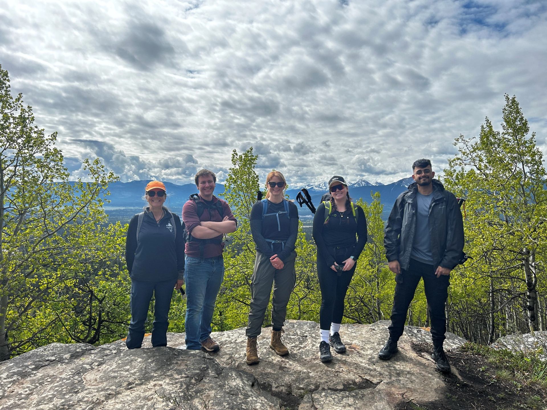 A group of people stood on a rock with trees in the background.
