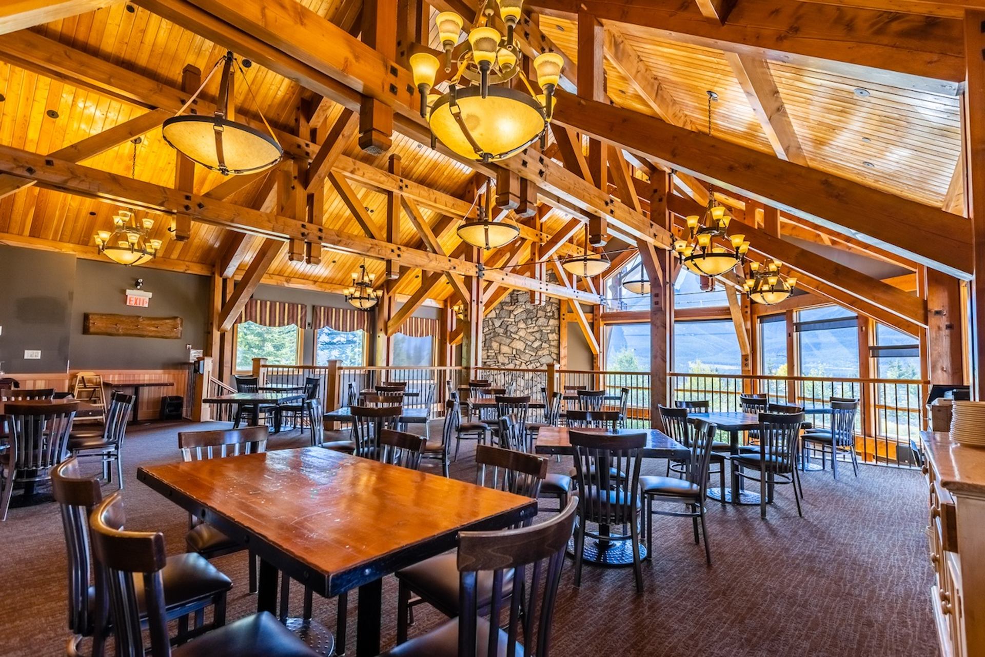  Spacious dining room with wooden beams, chandeliers, and mountain views through large windows.