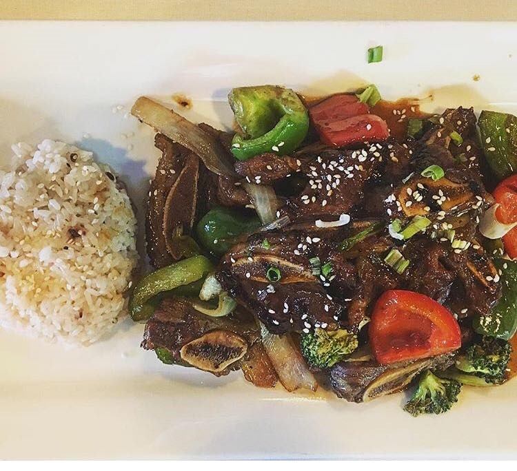 White rice with stir-fried meat, peppers, broccoli, and sesame garnish.