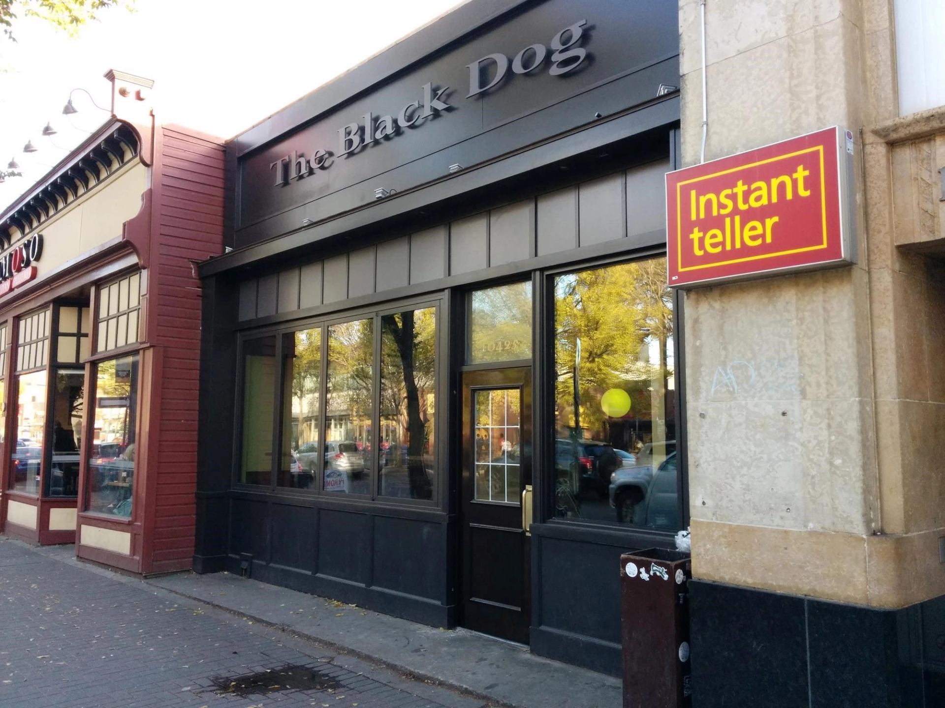 Exterior view of The Black Dog pub with large windows and signage on a city street.