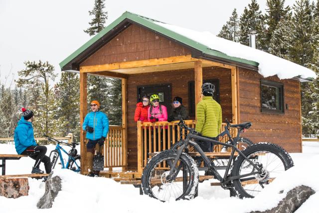 A group of fatbikers standing outside of warming hut after fatbiking in Castle Provincial Park