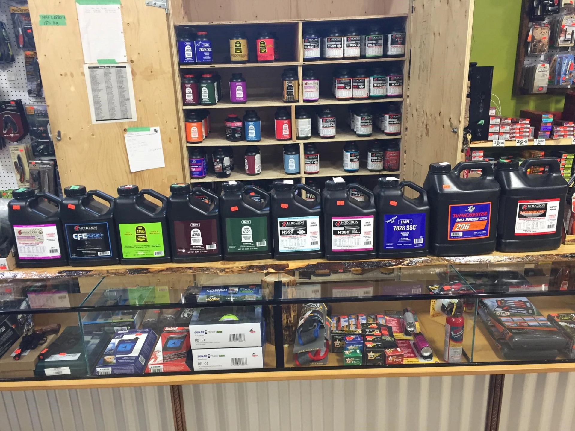 Ammo containers and powder jugs on a store shelf display, with product labels visible.
