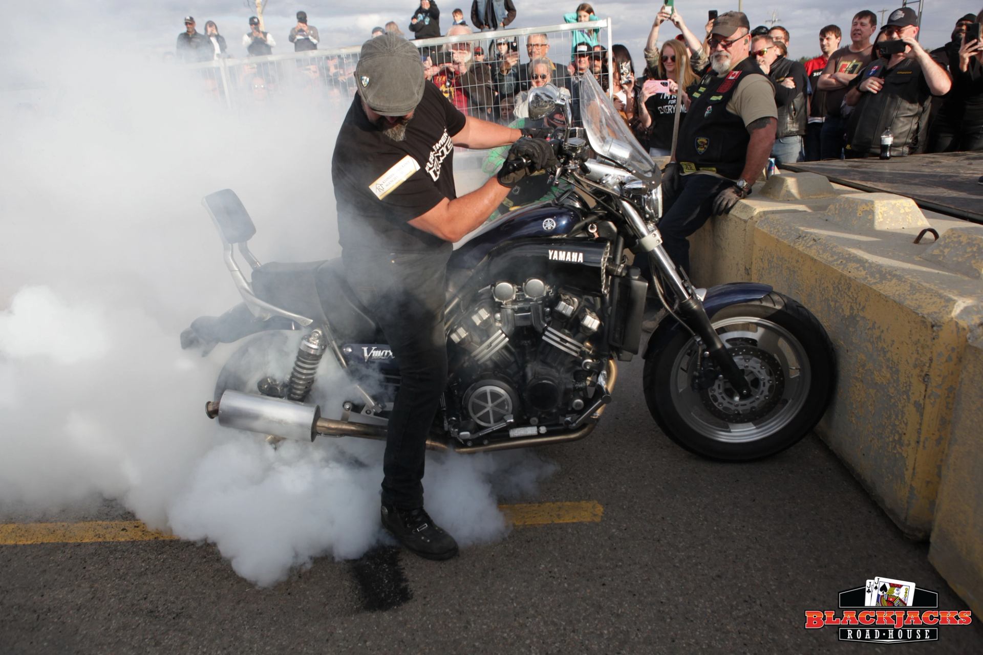 Motorcycle burnout competition with rider, crowd, and smoke rising from motorcycle exhaust.