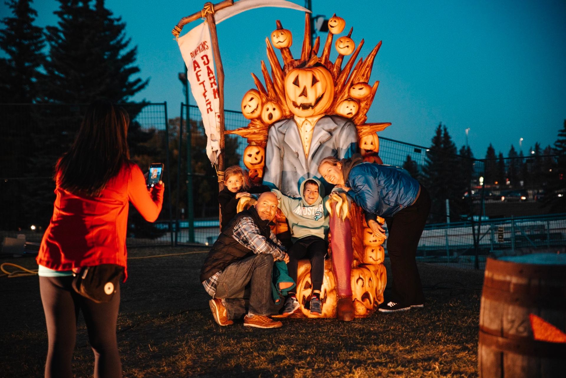 Family posing with kids on a spooky pumpkin throne at night