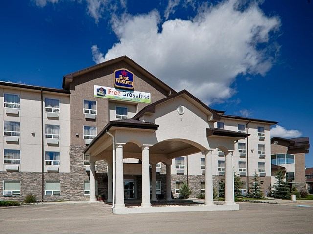 Exterior of Best Western Plus Inn & Suites with columned entrance and clear skies.
