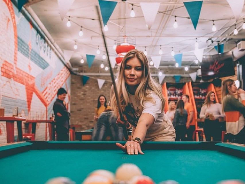 A woman playing pool in the billiards hall.
