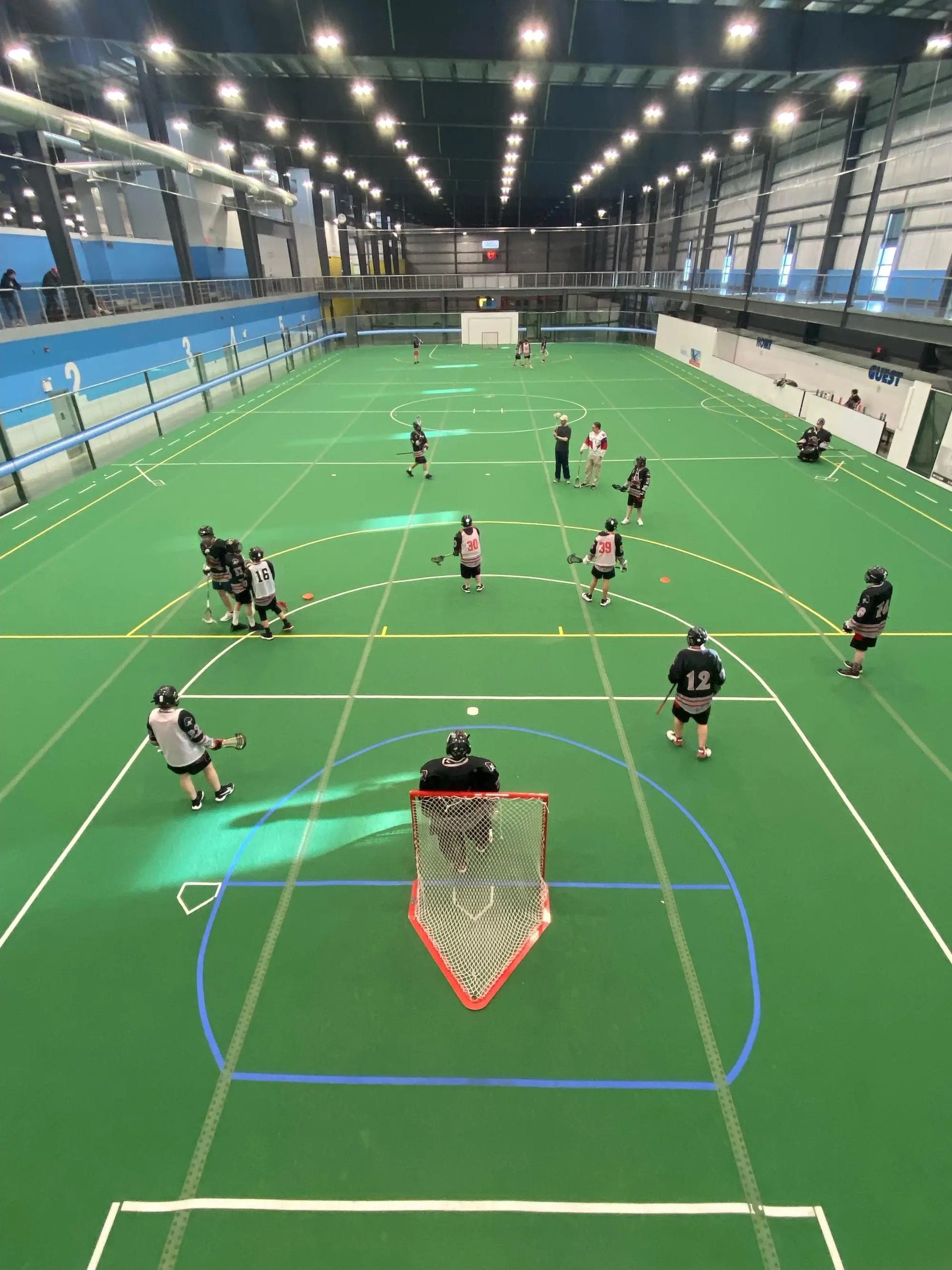 Players on green indoor field at Regional Field House, possibly playing lacrosse.