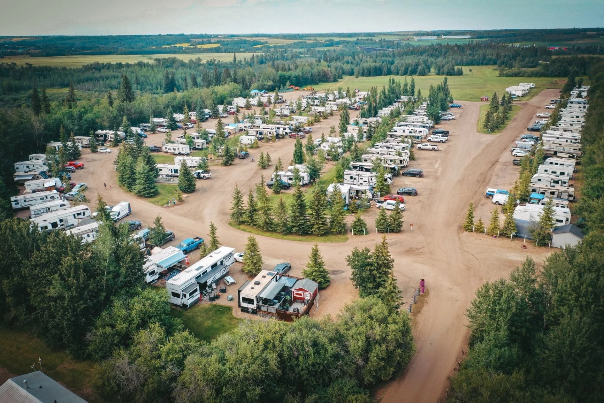 Aerial view of a large RV campground with gravel roads and surrounding forest.