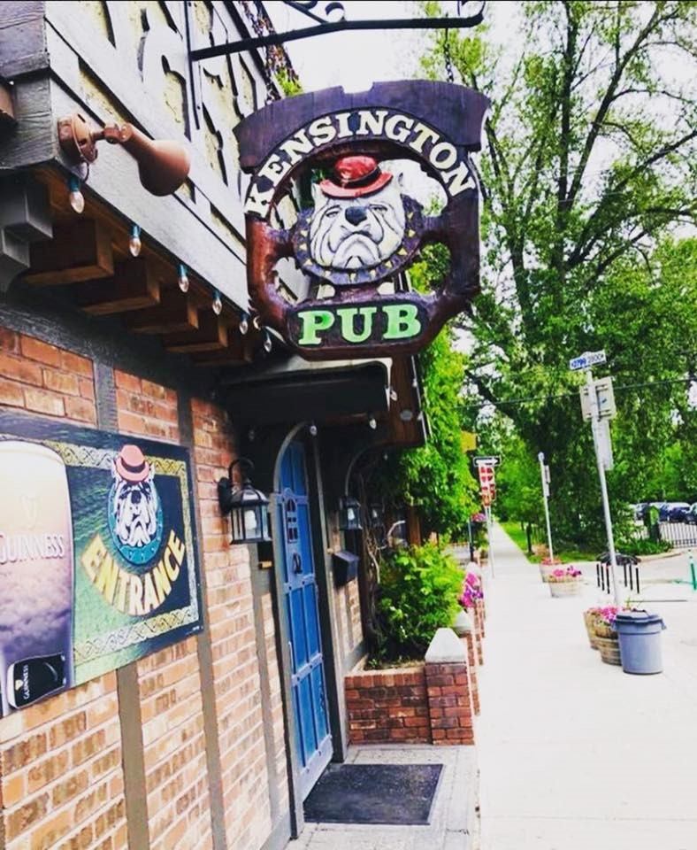 Kensington Pub exterior with brick facade, blue door, and bulldog logo signage.