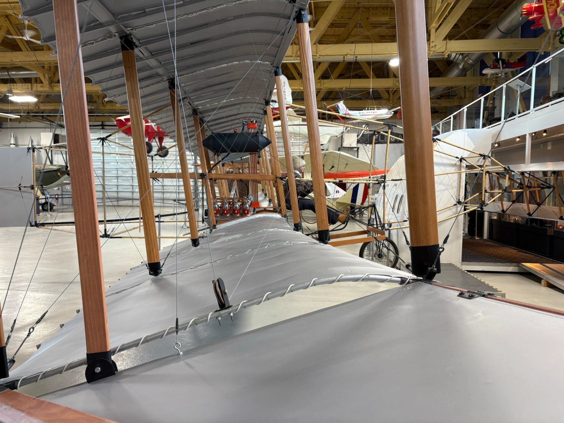 Close-up view of an early aircraft wing and wooden framework inside an aviation museum.