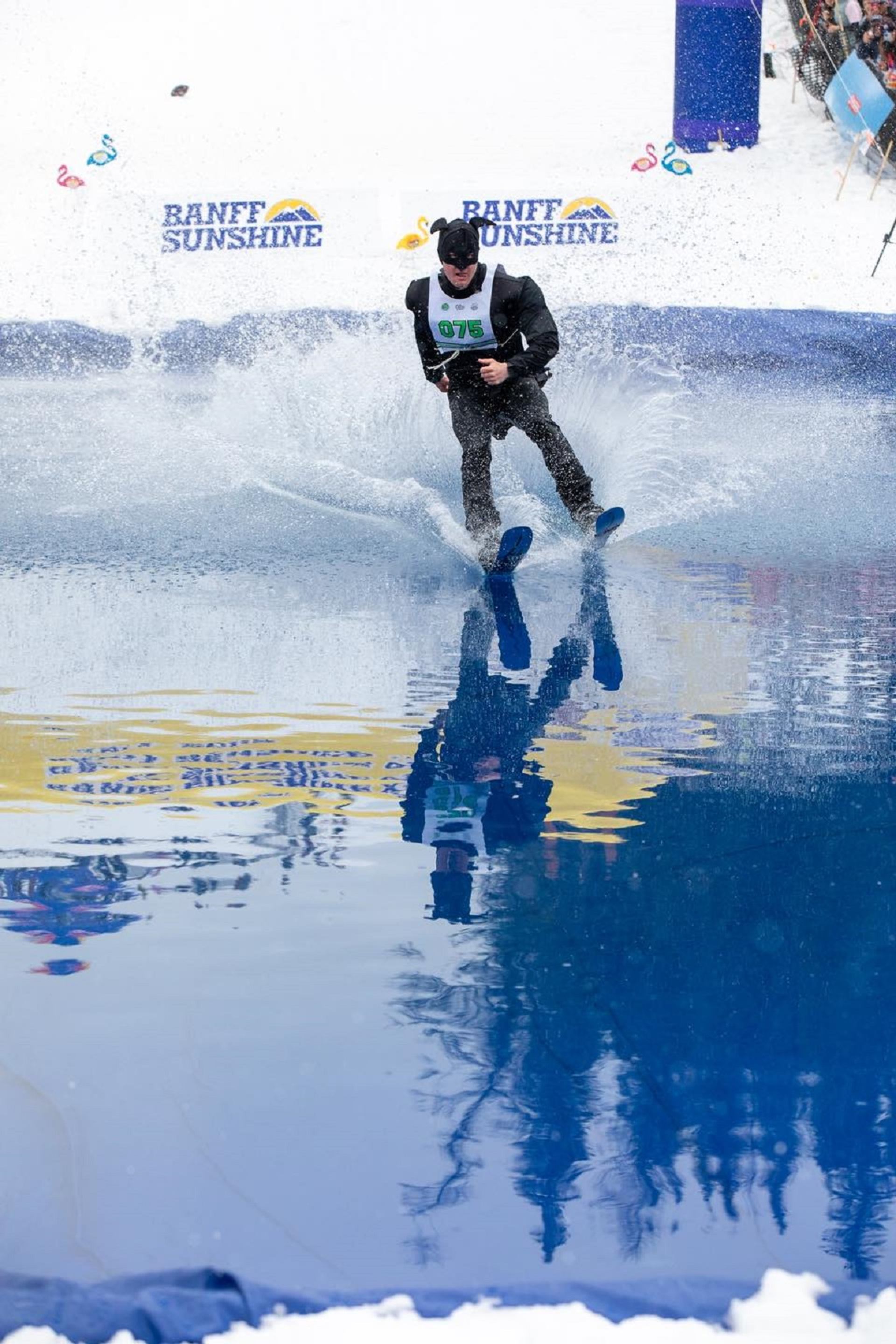 Skier skimming over a water pool during the Slush Cup event at Banff Sunshine Village.