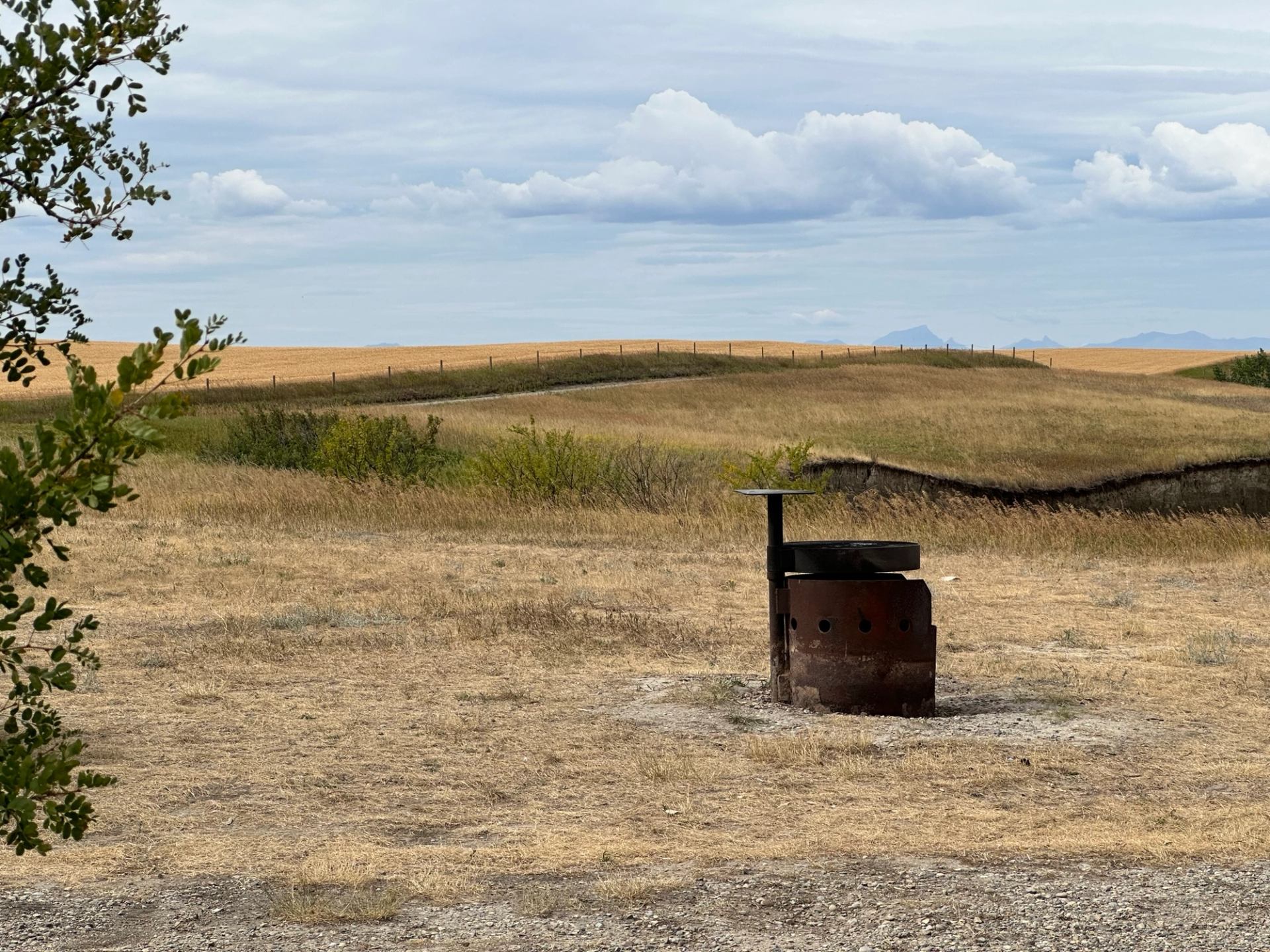 A metal fire ring on dry prairie grass with rolling hills in the background.