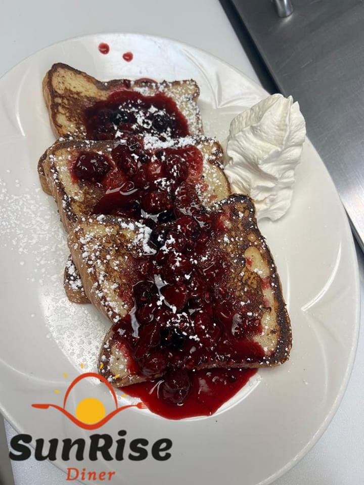 French toast with berry sauce, whipped cream, and SunRise Diner logo on a plate.
