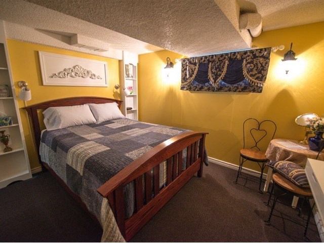 Cozy bedroom with yellow walls, wooden bed frame, and quilted bedding.