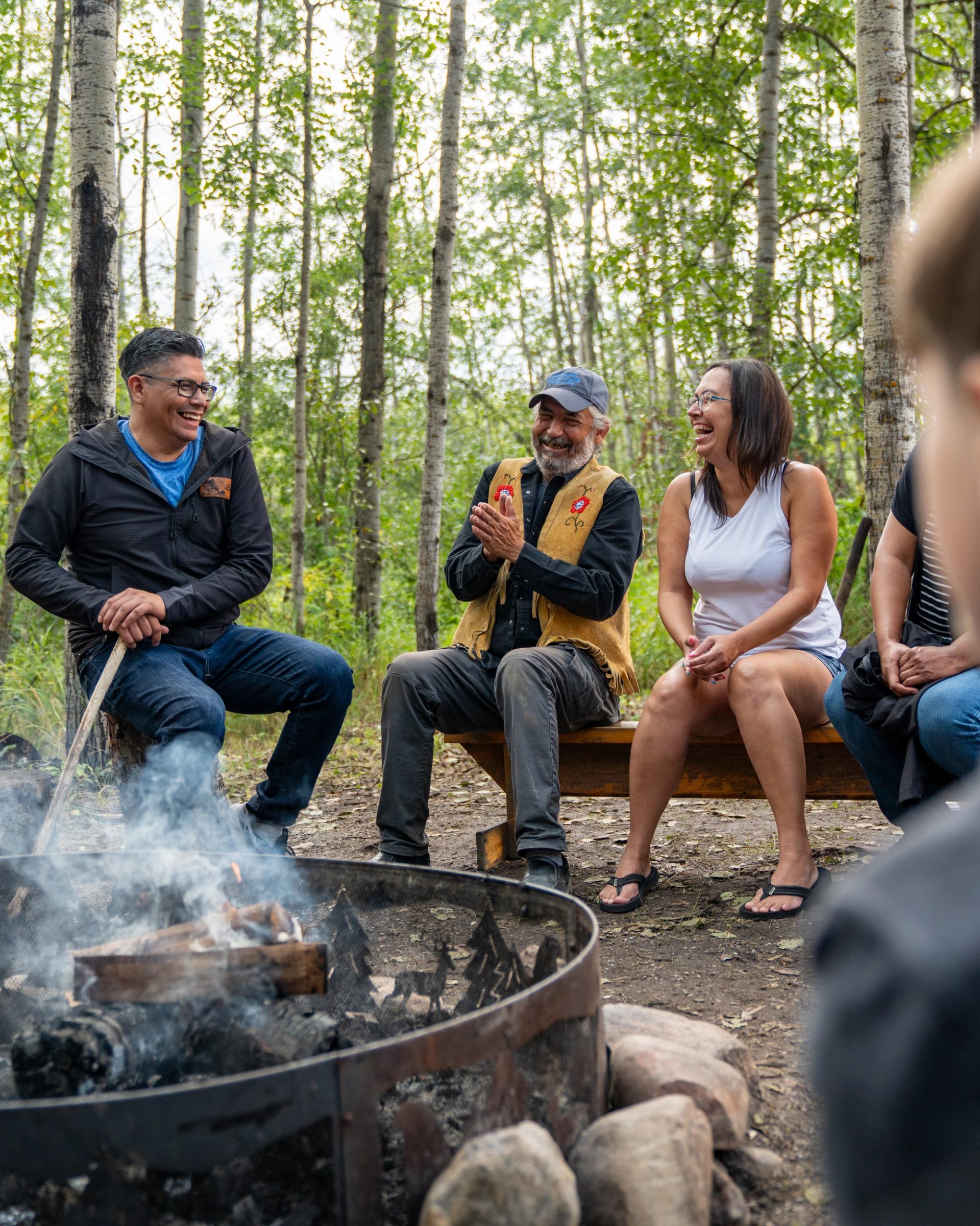 Group sitting around a campfire in a forest setting at Hideaway Adventure Grounds.