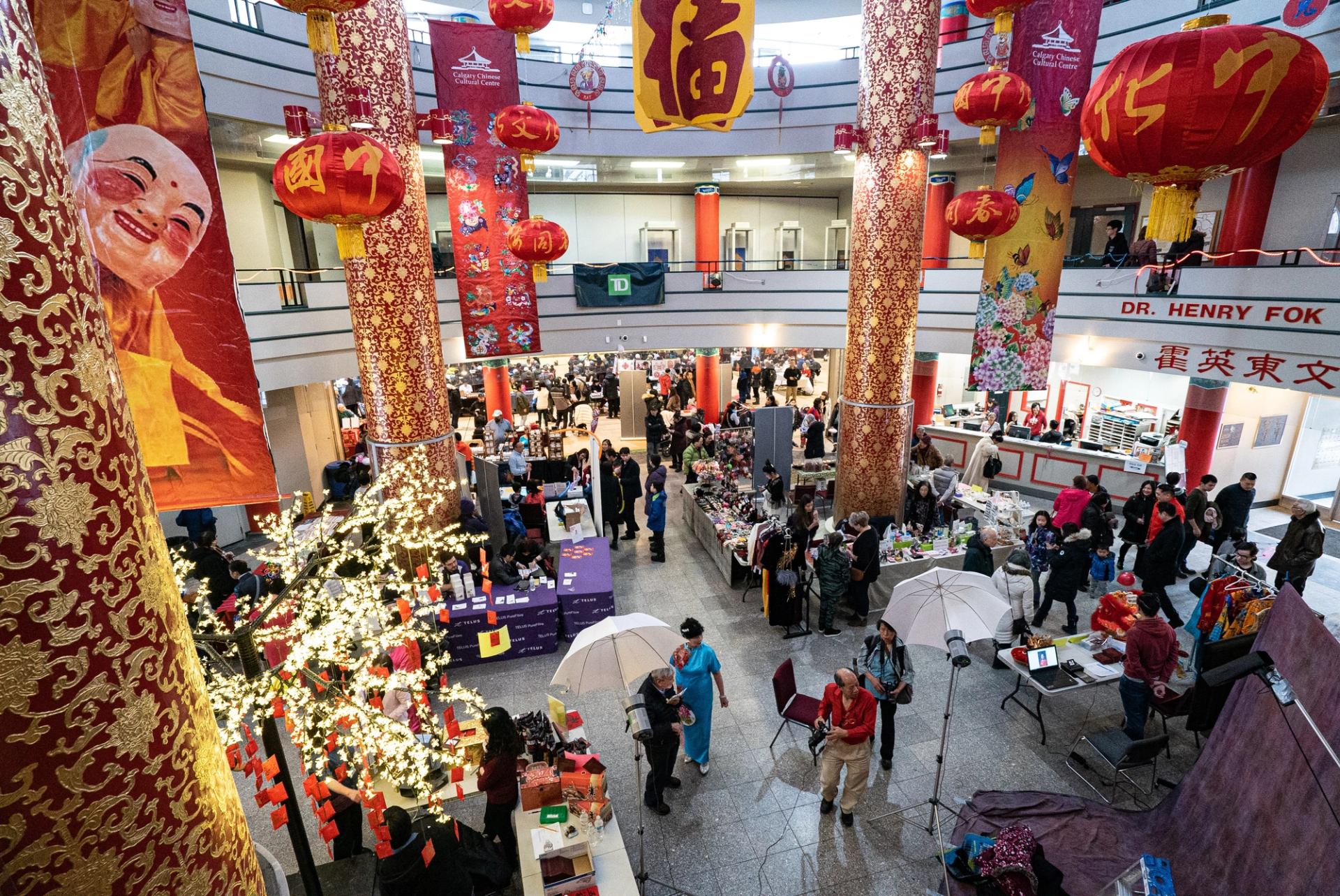 Indoor Chinese New Year market with red lanterns, banners, and festive decorations.