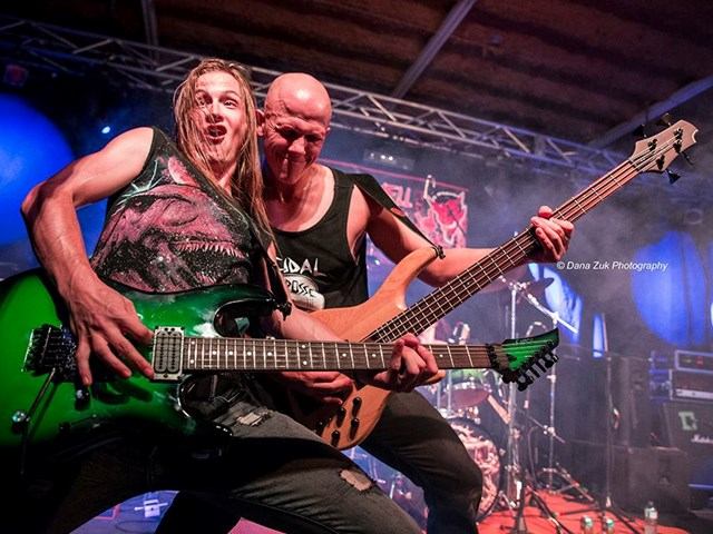 Two guitarists performing on stage with electric guitars at Loud As Hell Heavy Metal Festival.