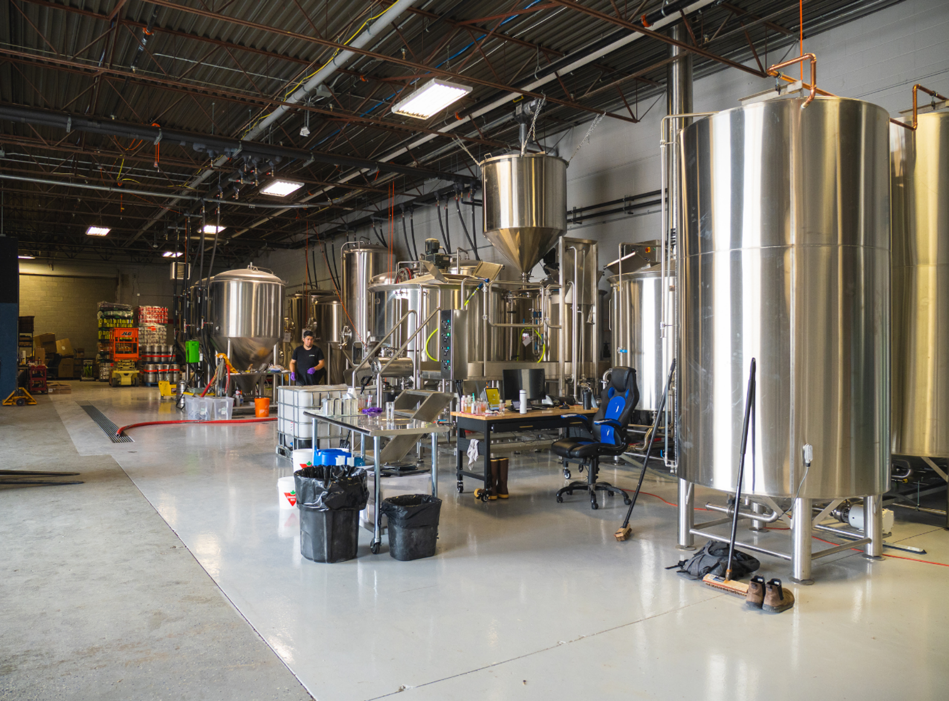 Stainless steel tanks and brewing equipment fill an industrial production facility.