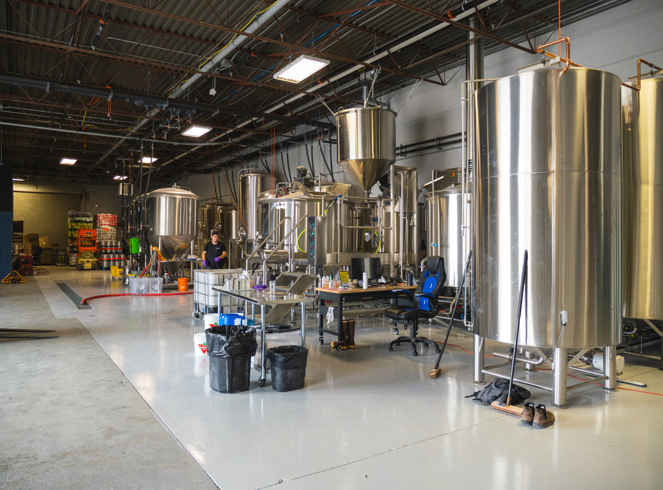 Stainless steel tanks and brewing equipment fill an industrial production facility.