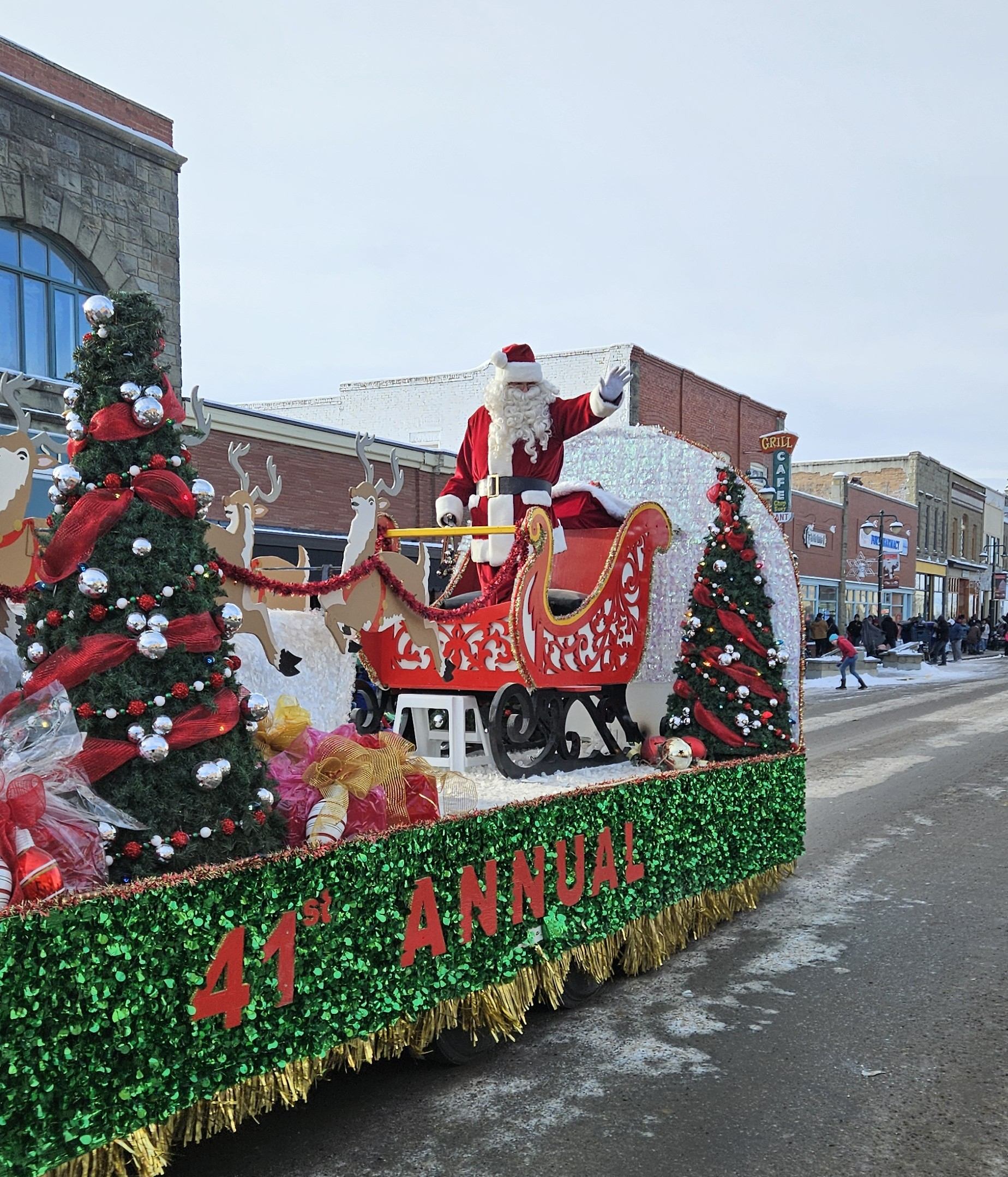Santa rides a red sleigh float with Christmas trees and gifts at Fort Macleod parade.