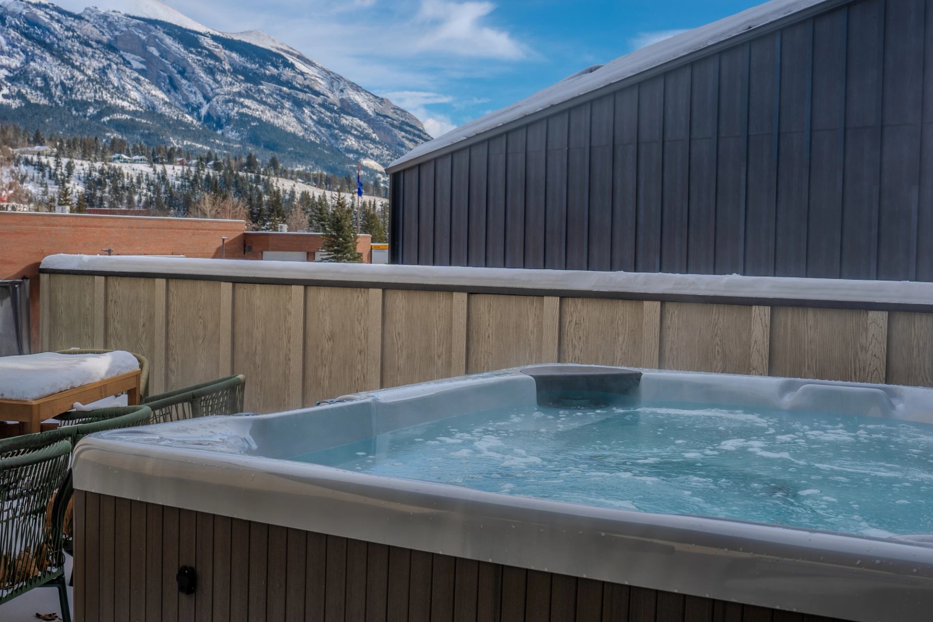 Outdoor hot tub with steaming water and snowy mountain views in the background.