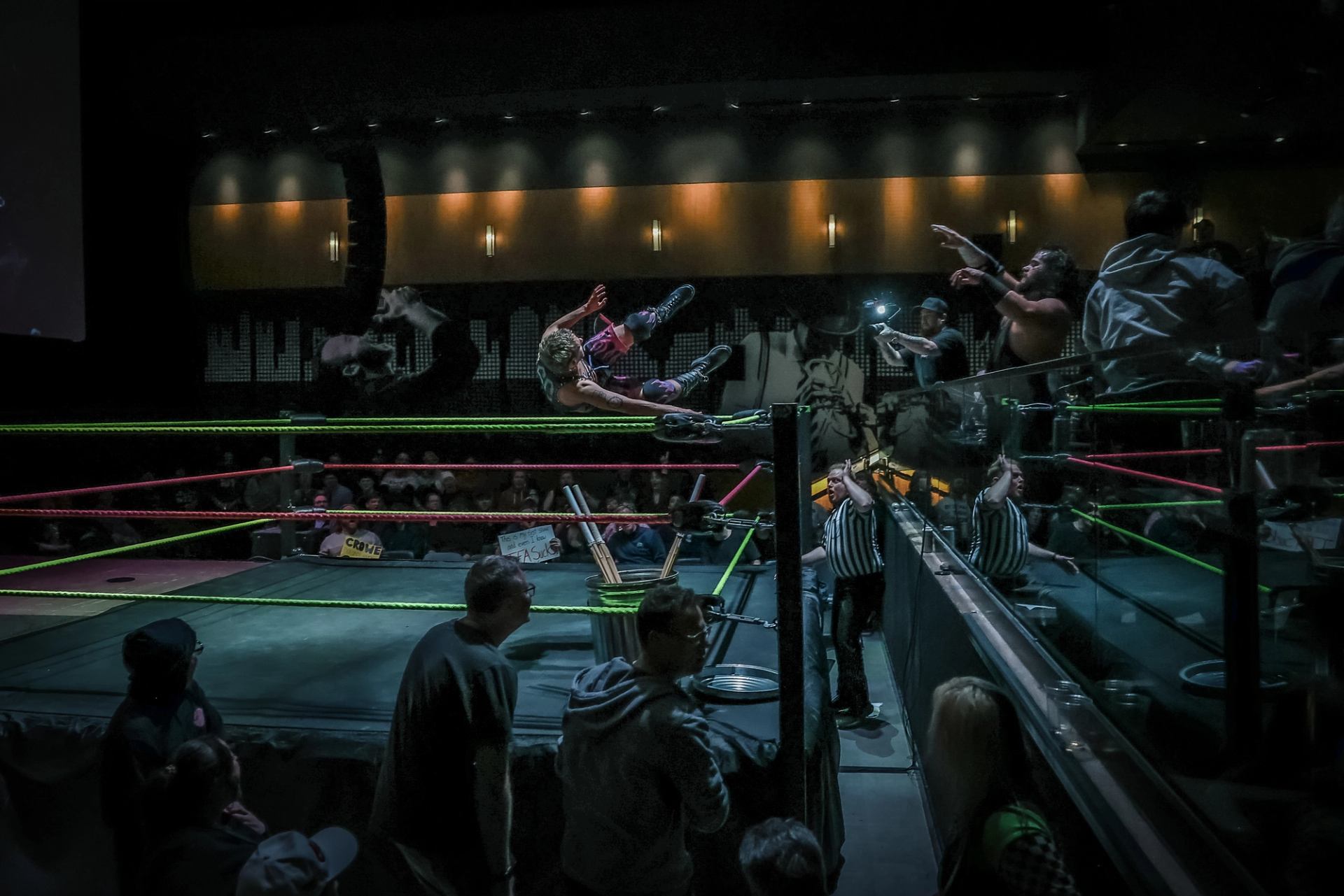 Wrestlers fly toward each other outside the ring in a dramatic move.
