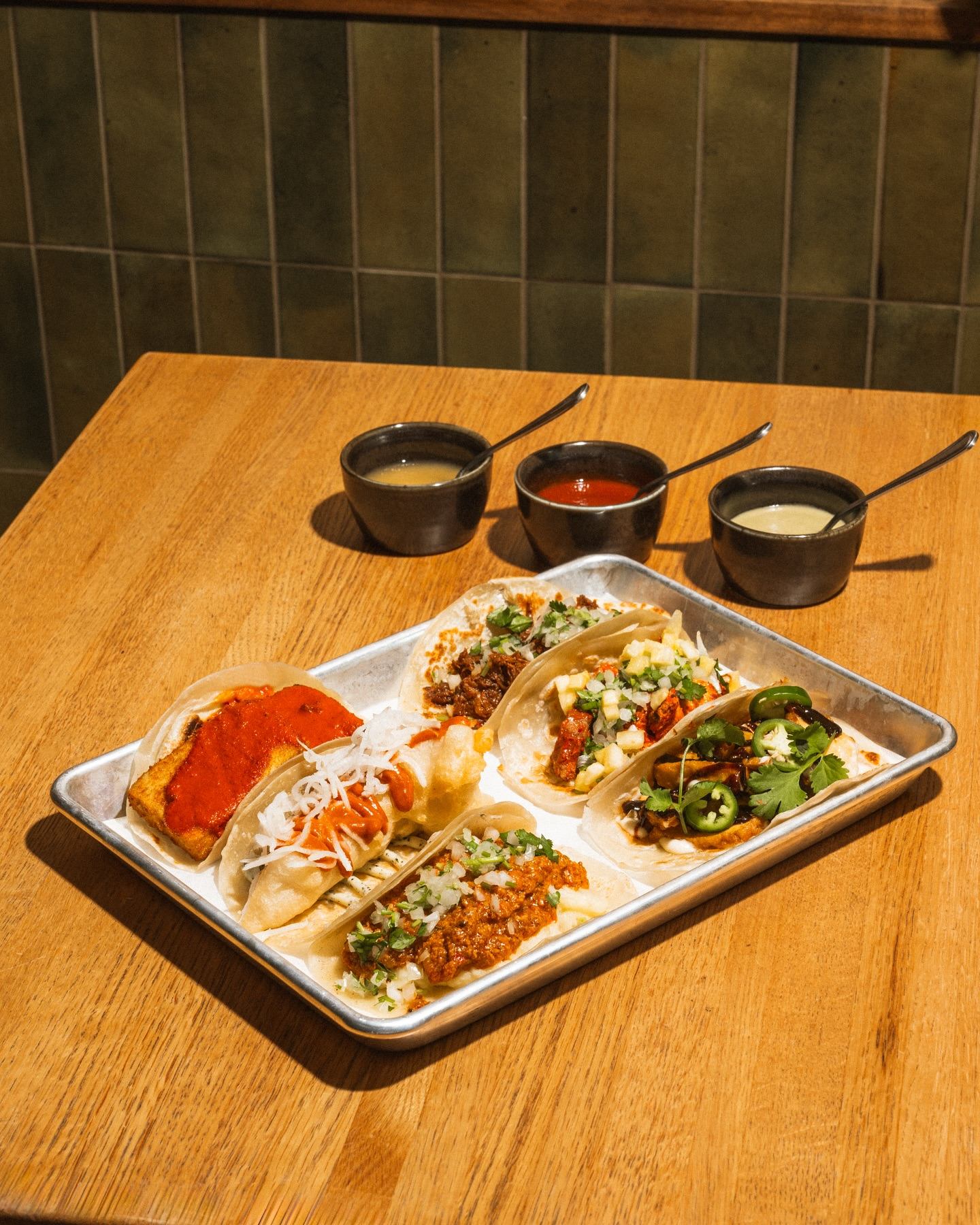 A variety of different tacos and sauces.