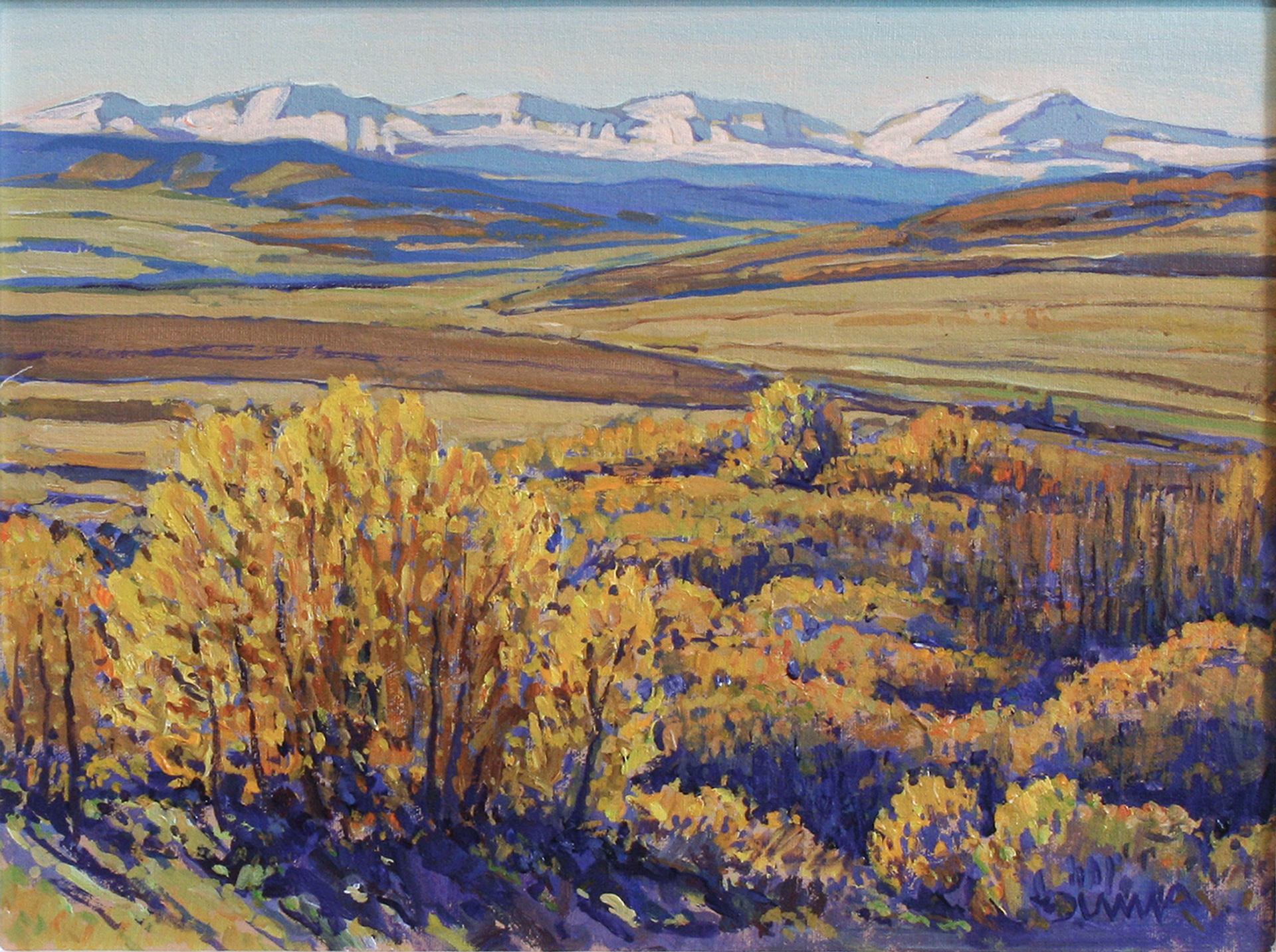 Autumn-toned hills and shrubs stretch toward pale blue mountains on the horizon.
