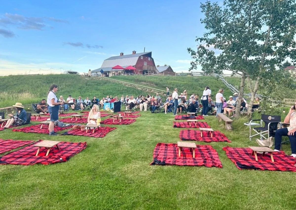 Old Red Barn welcomes guests to an outdoor gathering with picnic blankets on the lawn.