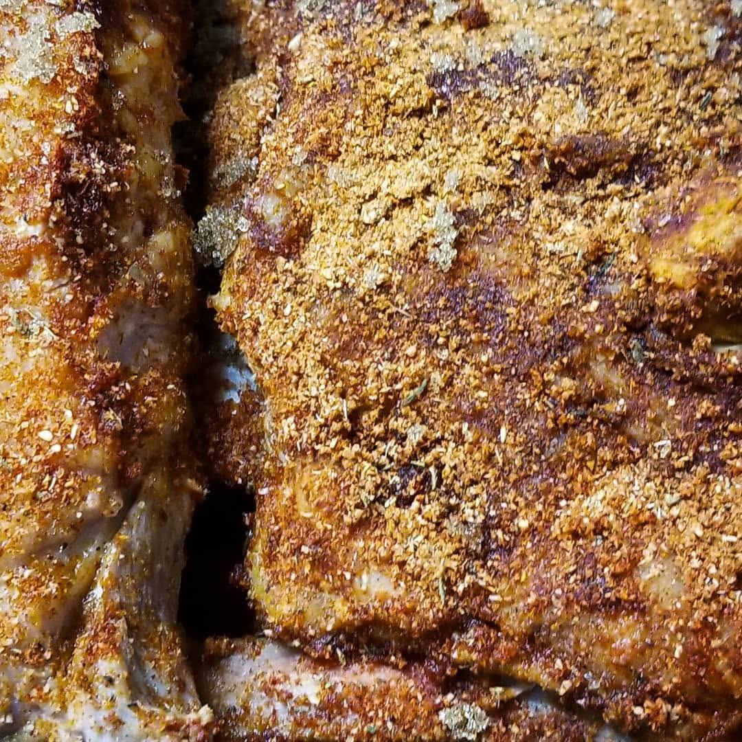 Close-up of cooked meat covered in coarse golden-brown dry spice rub.