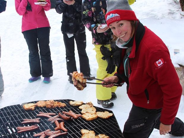 A woman grills during a dog sled excursion.