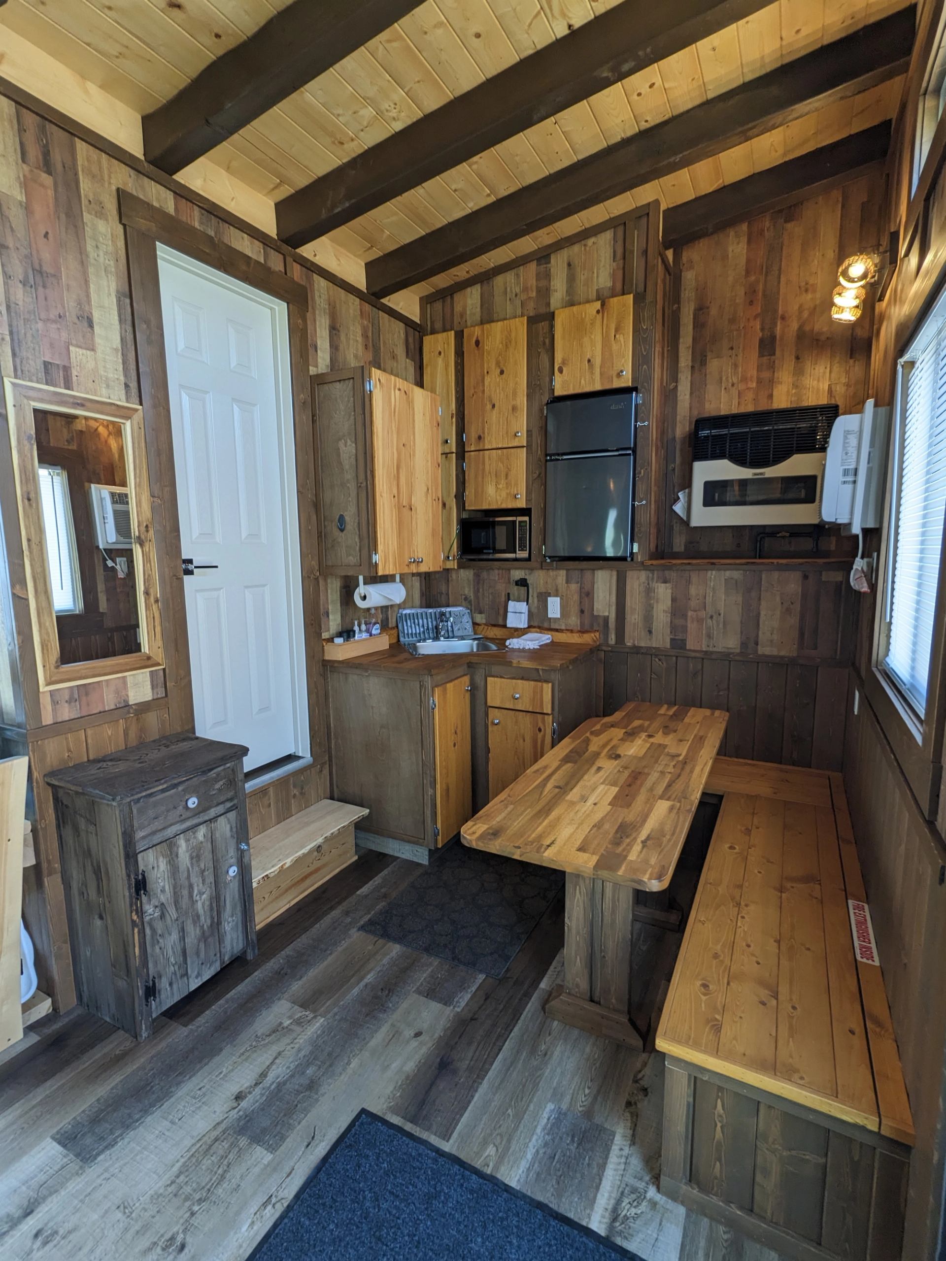 Wood-panelled kitchenette with appliances, sink, dining table and bench seating.