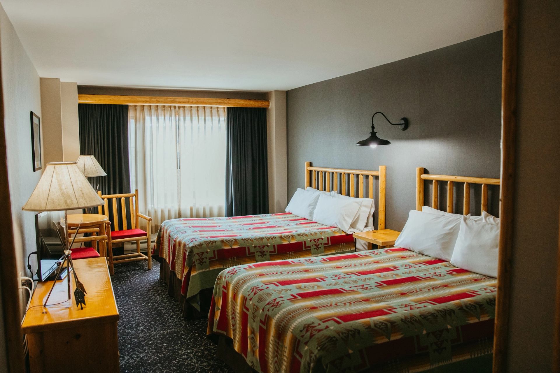 Lodge room with two double beds, patterned bedding, and warm wooden furnishings.