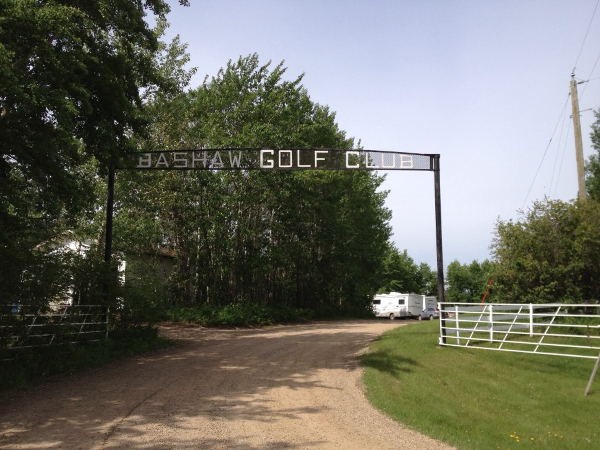 Entrance sign and gravel road lead into Bashaw Golf & Country Club and Campground.