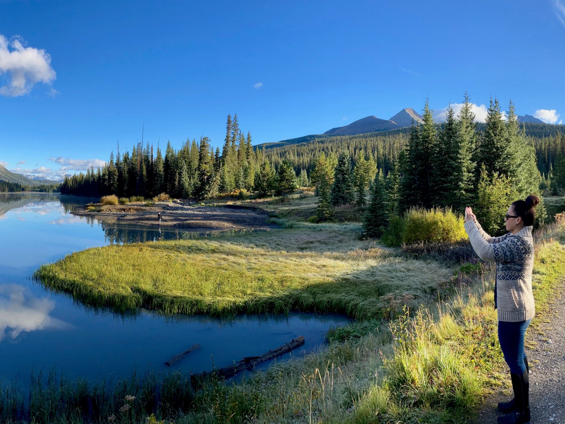 Person taking a photo of a serene river and forested mountains during Bow Valley Canyon Tour.