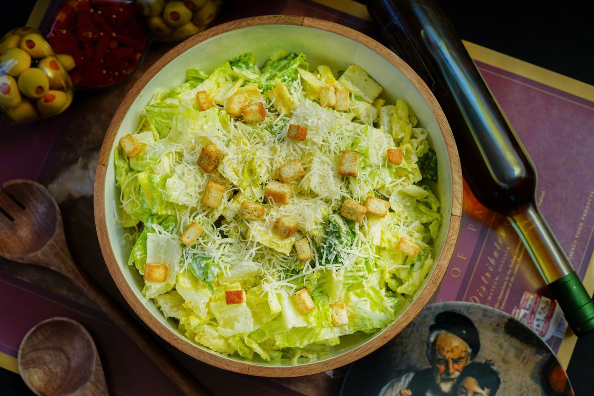 Caesar salad with romaine lettuce, grated cheese and croutons in a wooden bowl.