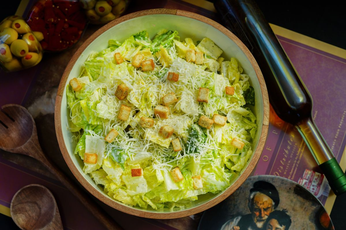 Caesar salad with romaine lettuce, grated cheese and croutons in a wooden bowl.