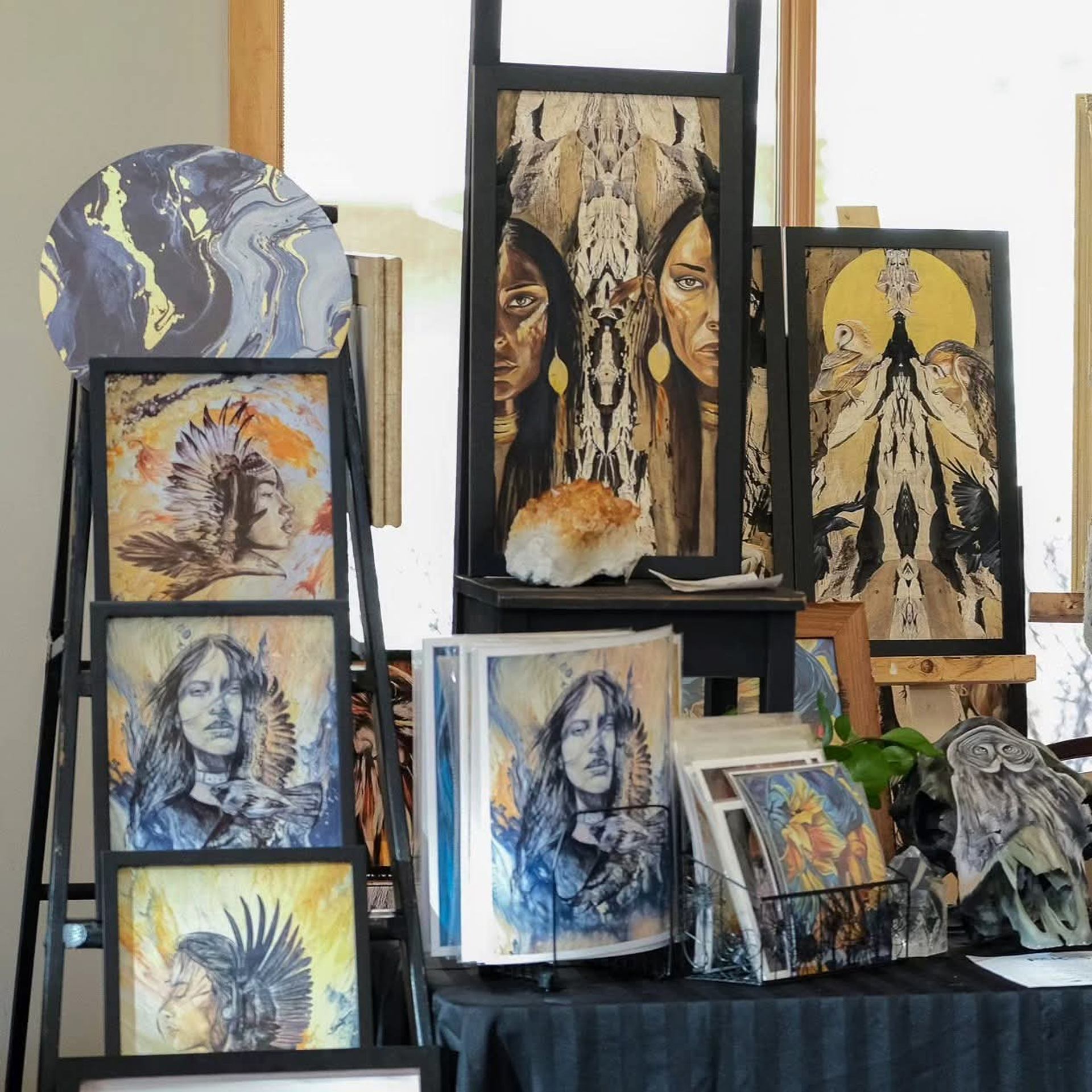 Artworks featuring Indigenous portraits and symbols displayed on easels and shelves.
