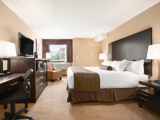 Days Inn room with king bed, desk, TV, and armchair in warm tones.