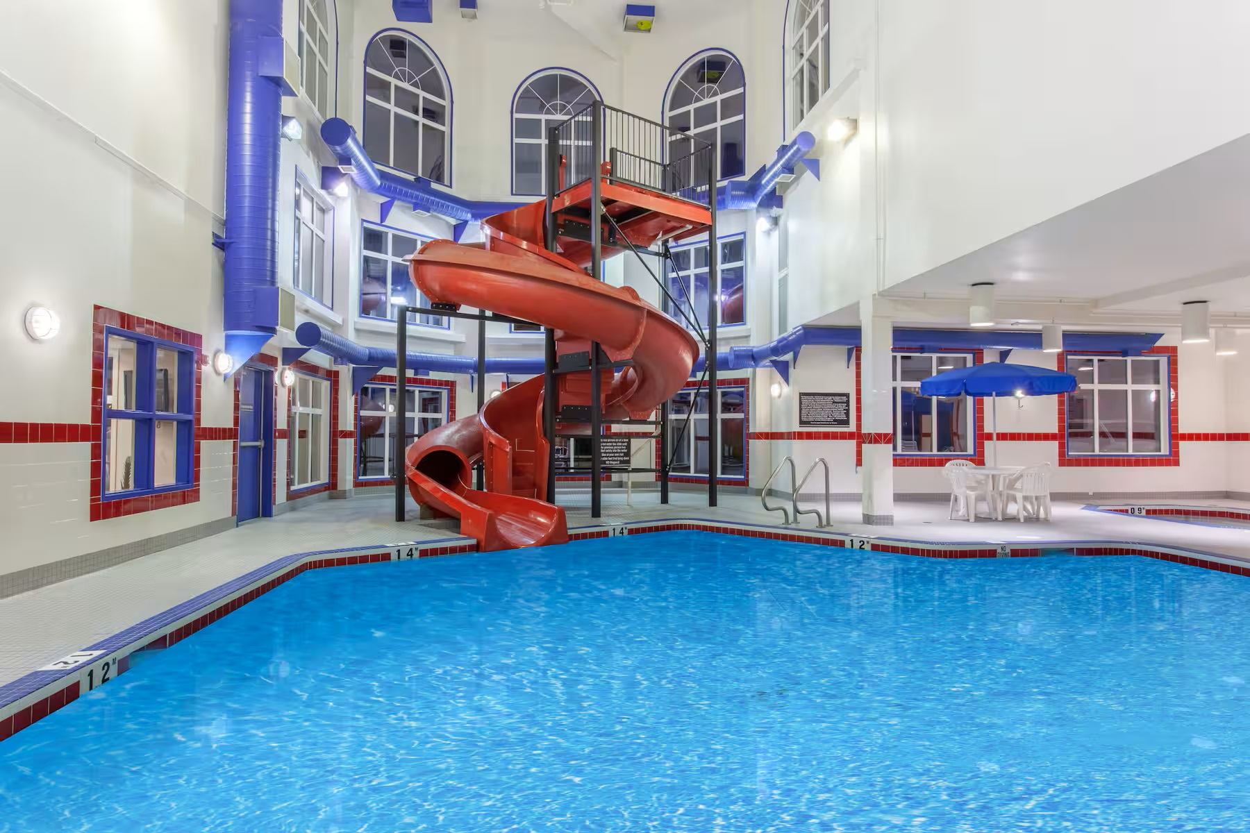 An indoor swimming pool with a large red spiral waterslide.