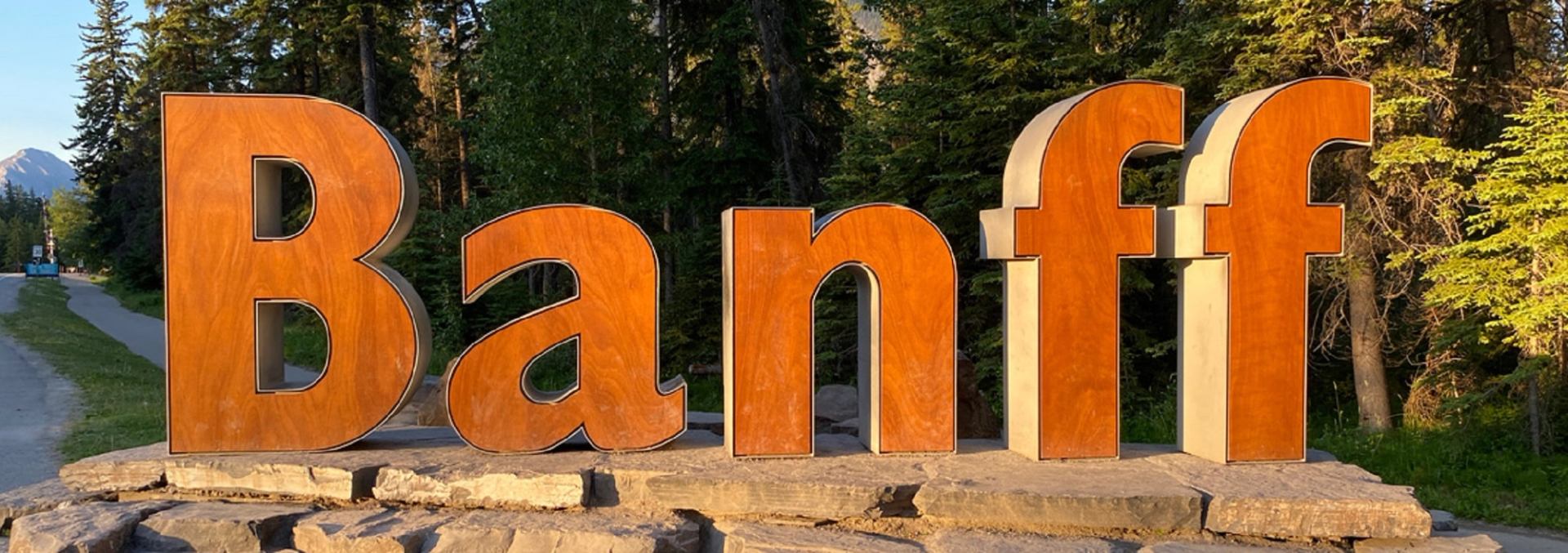 Large "Banff" sign with forest backdrop.