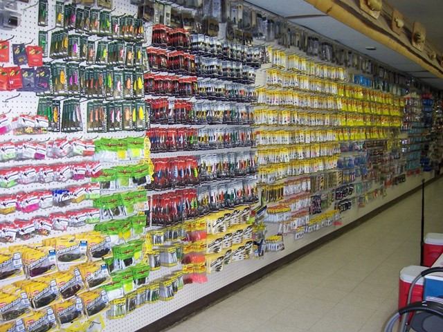 Pegboard wall lined with packaged fishing lures and tackle in a store aisle.