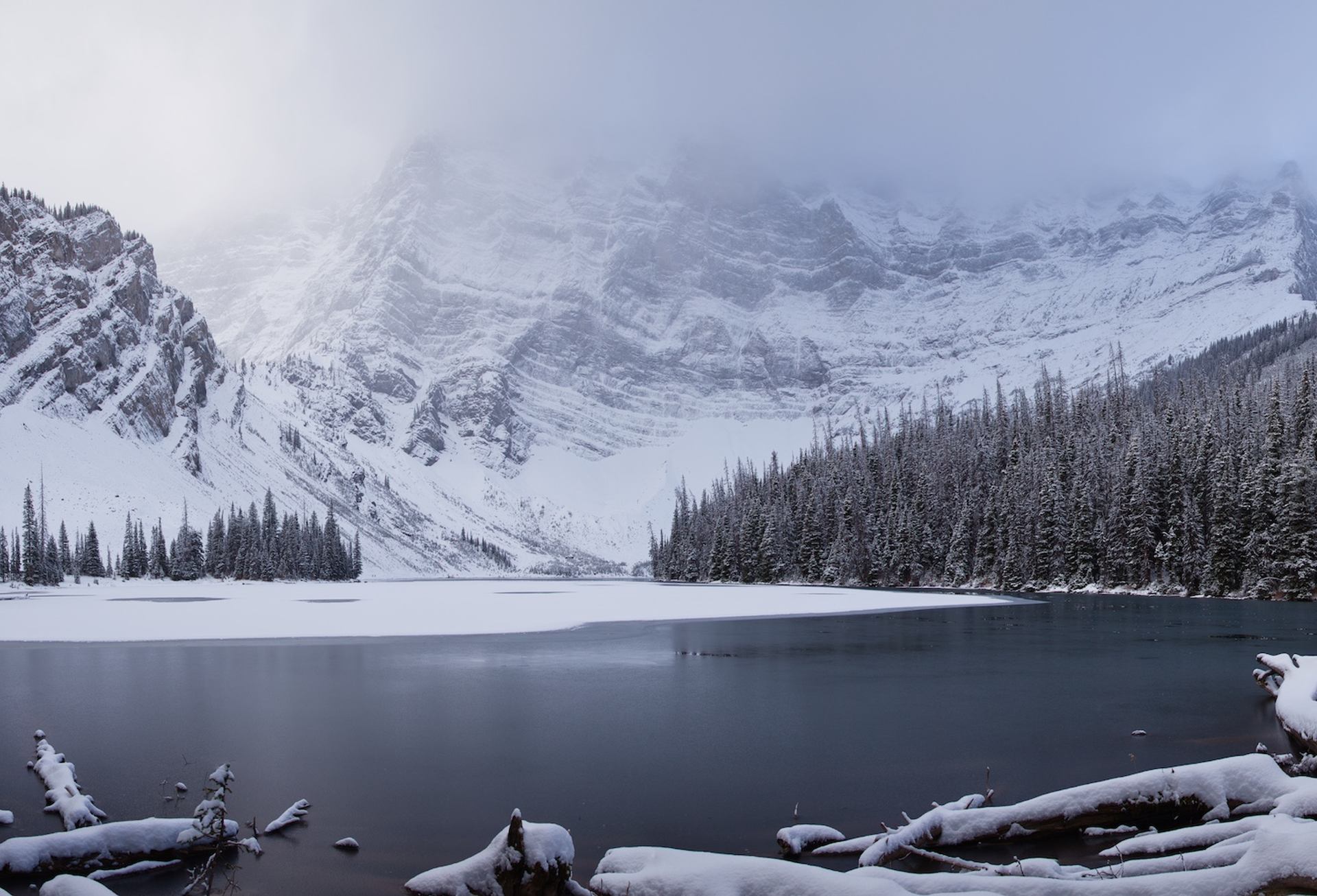 Snow-covered mountains and a partially frozen lake surrounded by dense forest on Rawson Lake.