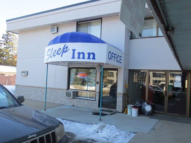 Exterior view of Sleep Inn Motel entrance with blue awning and office sign.
