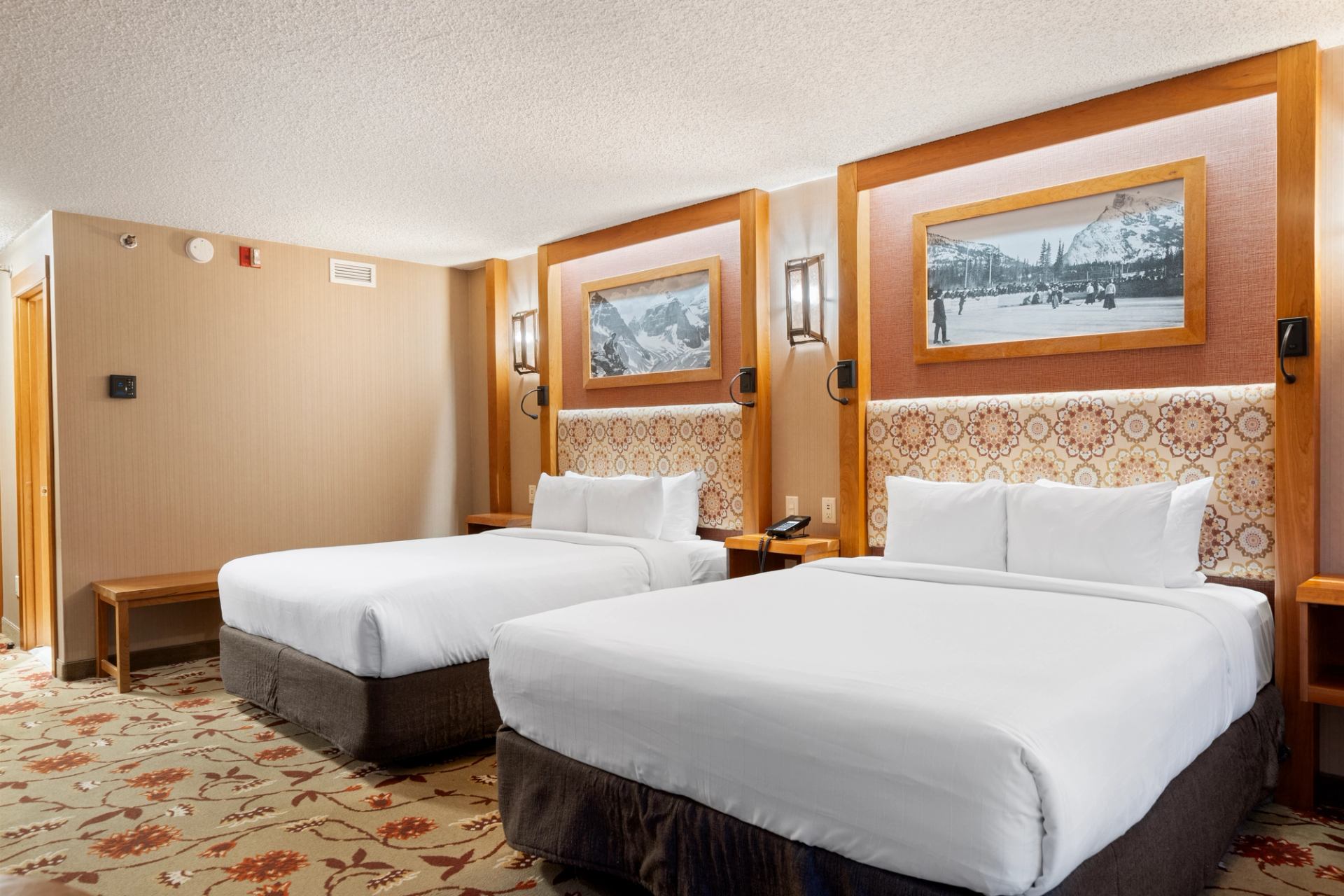 Warm room with two beds and mountain-themed decor.