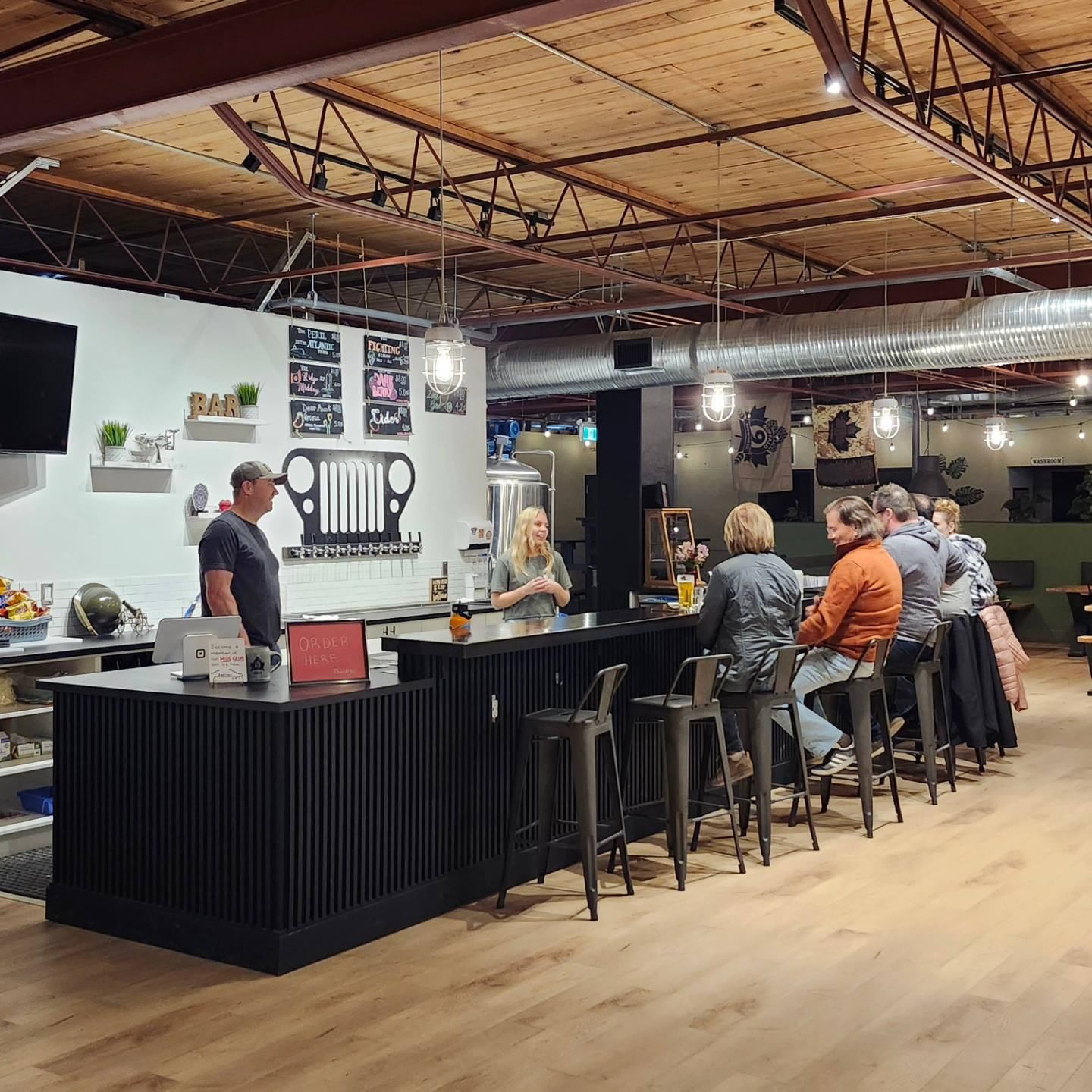 A group of people sat to the bar at the taproom.