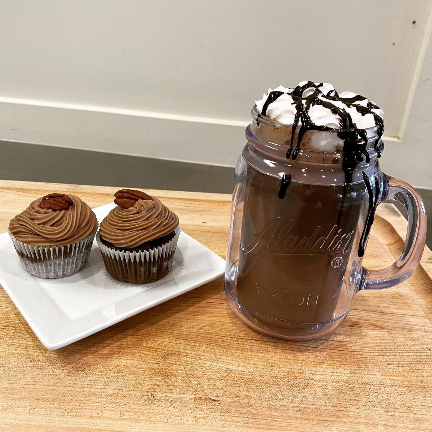 Chocolate cupcakes and hot chocolate with whipped cream on a wooden table.