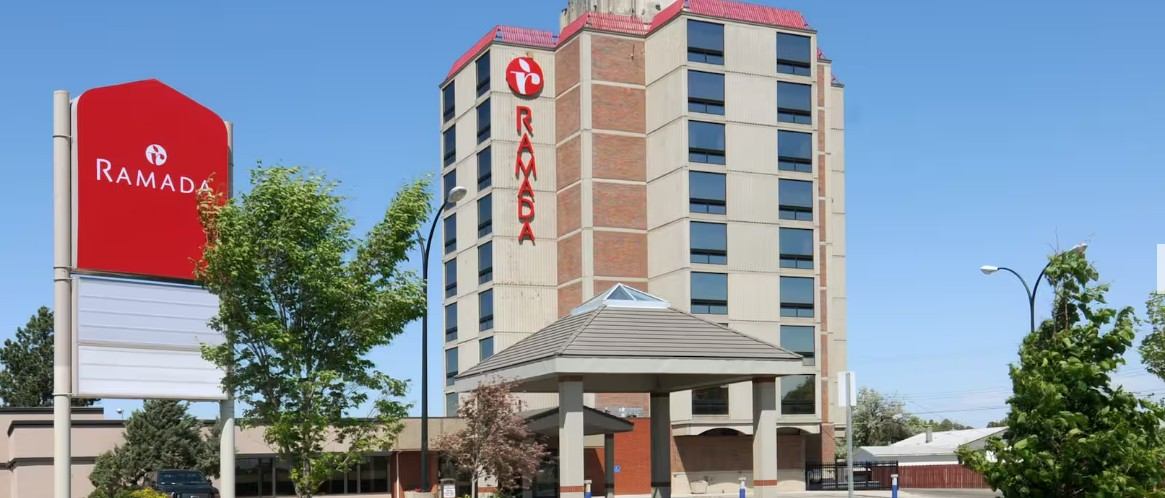 Exterior of Ramada hotel with tall building, entrance canopy, and signage.