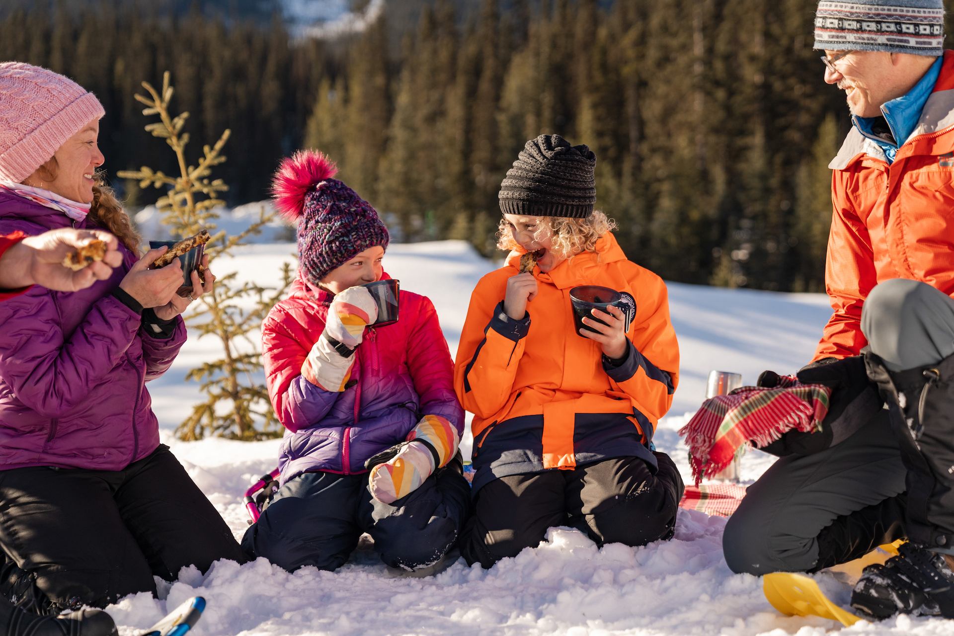 Children enjoying hot chocolate and home baked goodies on a snowshoeing tour.
