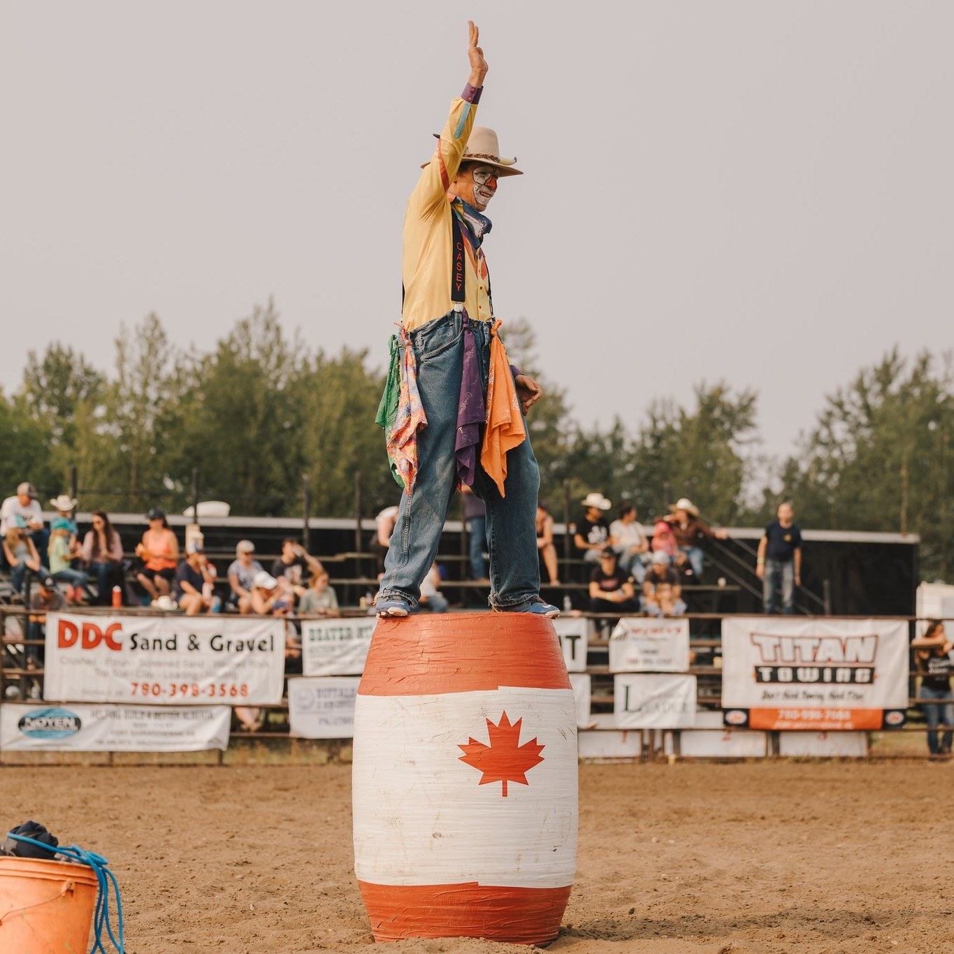 Rodeo clown standing on a barrel with his hand over his head